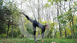 Young woman practices yoga in a city park On the grass