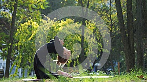 Young woman practices yoga in a city park On the grass