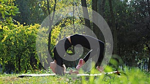 Young woman practices yoga in a city park On the grass