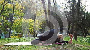 Young woman practices yoga in a city park on the grass