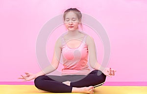 Young woman practices yoga and meditates in the lotus position