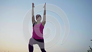 A young woman practices yoga on a mountain in the background of a big city