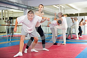 Young woman practicing elbow blow with wristlock to opponent in gym