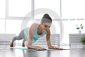 Young woman practicing forearm plank asana in studio. Phalakasana variation pose