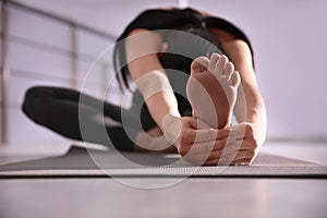 Young woman practicing head to knee asana in yoga studio. Janu Sirsasana pose