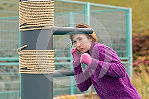 Young woman practicing martial arts alone on the sports ground with traditional dummies