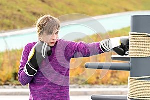 Young woman practicing martial arts alone on the sports ground with traditional dummies