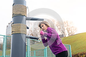 Young woman practicing martial arts alone on the sports ground with traditional dummies