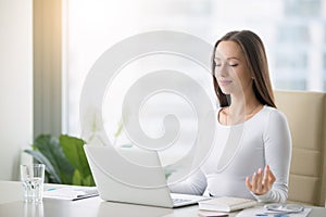 Young woman practicing meditation at the office desk