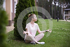 Young woman practicing morning meditation in nature at the park. Health lifestyle concept.