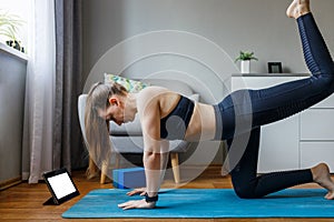 Young woman practicing online class yoga at home