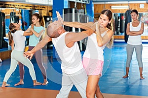 Young woman practicing palm heel strike to man in self-defense training in gym