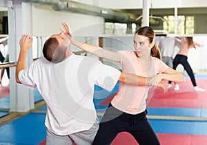 Young woman practicing palm strike with man in self defense training