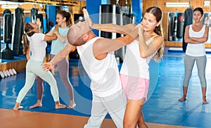 Young woman practicing palm strike with man in self defense training