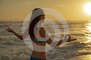 Young woman practicing pranayama and meditation at the beach. Hands in gyan mudra. Anti stress. Melasti beach, Bali, Indonesia