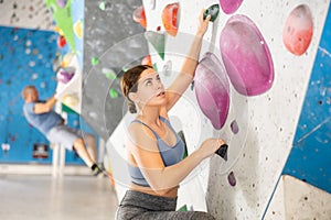 Young woman practicing rock climbing on climbing wall