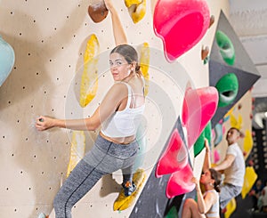 Young woman practicing rock climbing on climbing wall