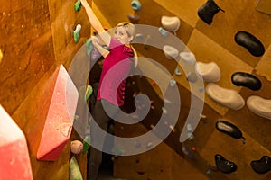 Young woman practicing rock-climbing on a rock wall indoors