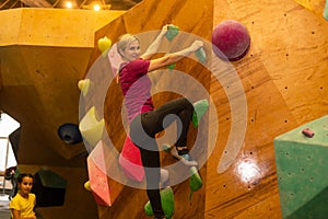 Young woman practicing rock-climbing on a rock wall indoors