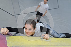 Young woman practicing rock-climbing on rock wall indoors