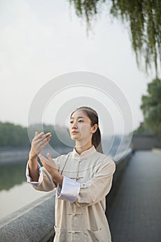 Young Woman Practicing Tai Ji, Arms Out Front, By the Canal