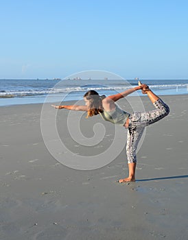 Young woman practicing yoga on the beach.