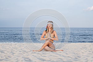 Young woman practicing yoga on the beach in Gomukasana pose