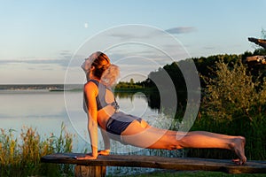 Young woman practicing yoga on the beach at sunset