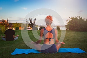 Young woman practicing yoga on the beach at sunset