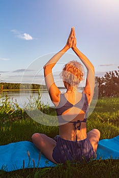 Young woman practicing yoga on the beach at sunset