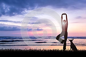 Young woman practicing yoga at beach on sunset