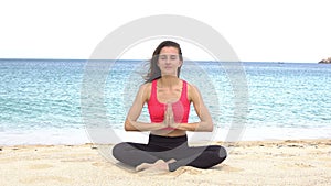 Young woman practicing yoga on the beach at sunset. Exercises calmness and harmony. Meditation in lotus pose. Healthy