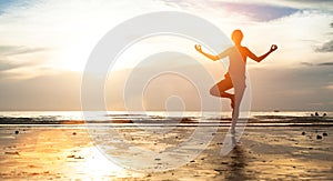 Young woman practicing yoga on the beach at sunset. Meditation.