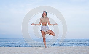 Young woman practicing yoga on the beach. Vrksasana pose