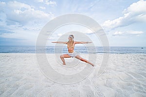 Young woman practicing yoga on the beach. Warrior pose