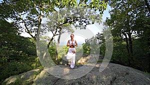 Young woman is practicing yoga at beautiful exotic place on the top of a mountain in slow motion. Yoga and meditation