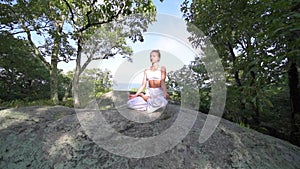 Young woman is practicing yoga at beautiful exotic place on the top of a mountain in slow motion. Yoga and meditation