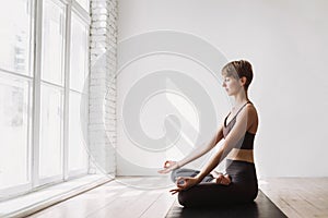 Young woman practicing yoga at class. Beautiful girl doing exercises at home.