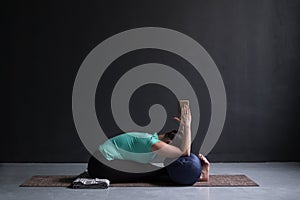 Woman practicing yoga, Seated forward bend pose, using block and bolster photo