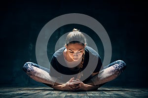 Young woman practicing yoga doing reclined goddess pose asana in dark room