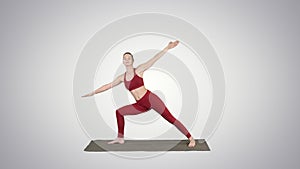 Young woman practicing yoga, finishes doing Utthita parsvakonasana exercise on gradient background.