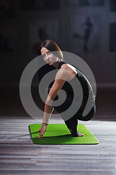 Young woman practicing yoga on green mat