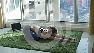 Young woman practicing yoga at home with cityscape background