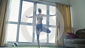 Young woman practicing yoga at home with cityscape background