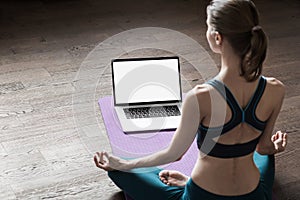 Young woman practicing yoga at home, online video training class, girl doing exercises and meditate