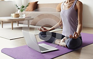 Young woman practicing yoga at home. Online video training. Girl doing exercises and meditate.