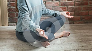 Young woman practicing yoga indoors. Close-up of female hands in lotus pose