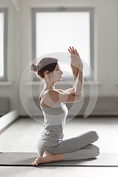 Young woman practicing yoga in light room making beautiful asana exercises