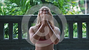 Young woman practicing yoga, meditates, prays outdoors, holds her hands together
