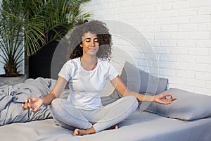 Young woman practicing yoga meditation on her bed